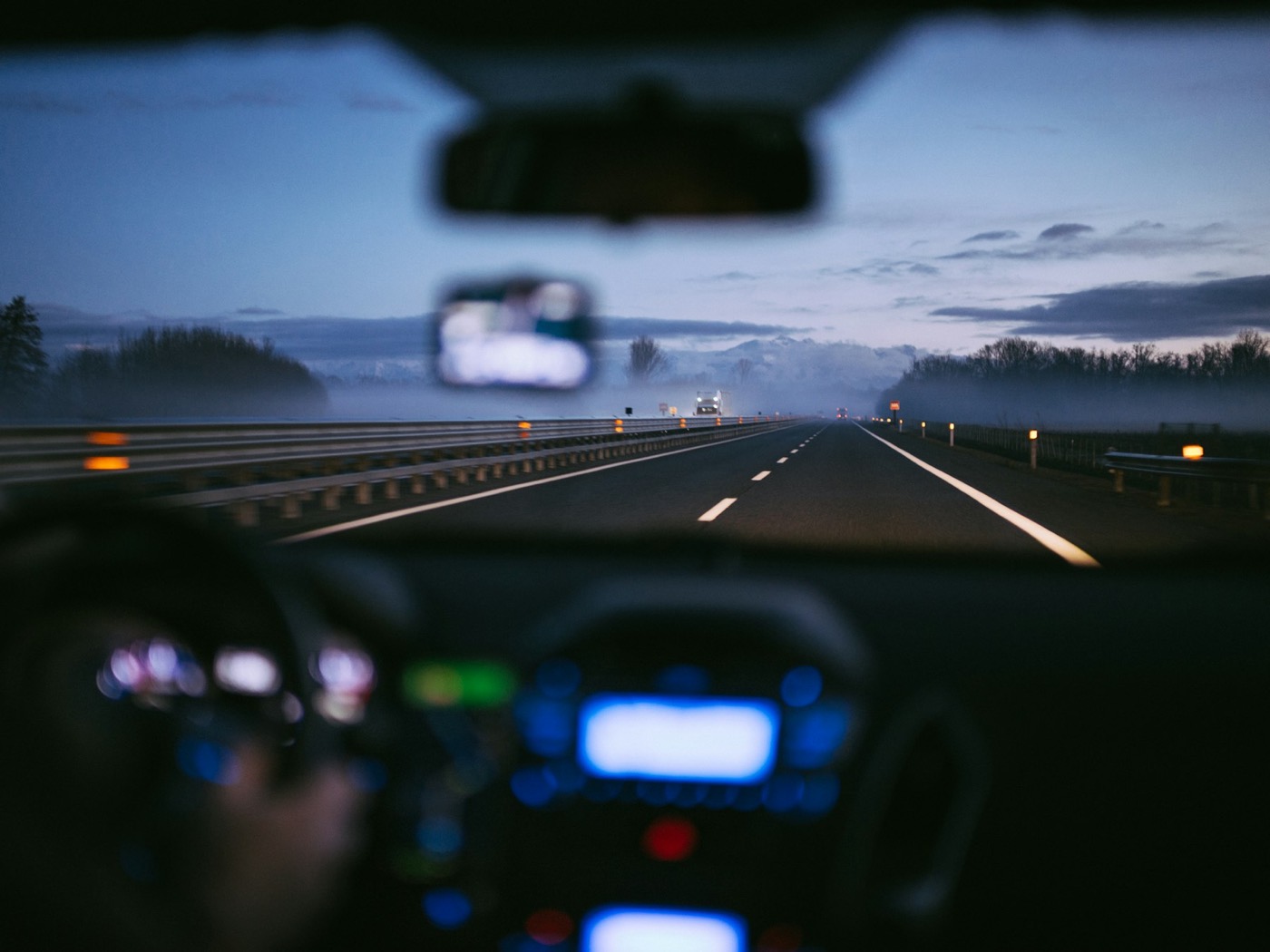 A dark road ahead seen from inside a car at dusk