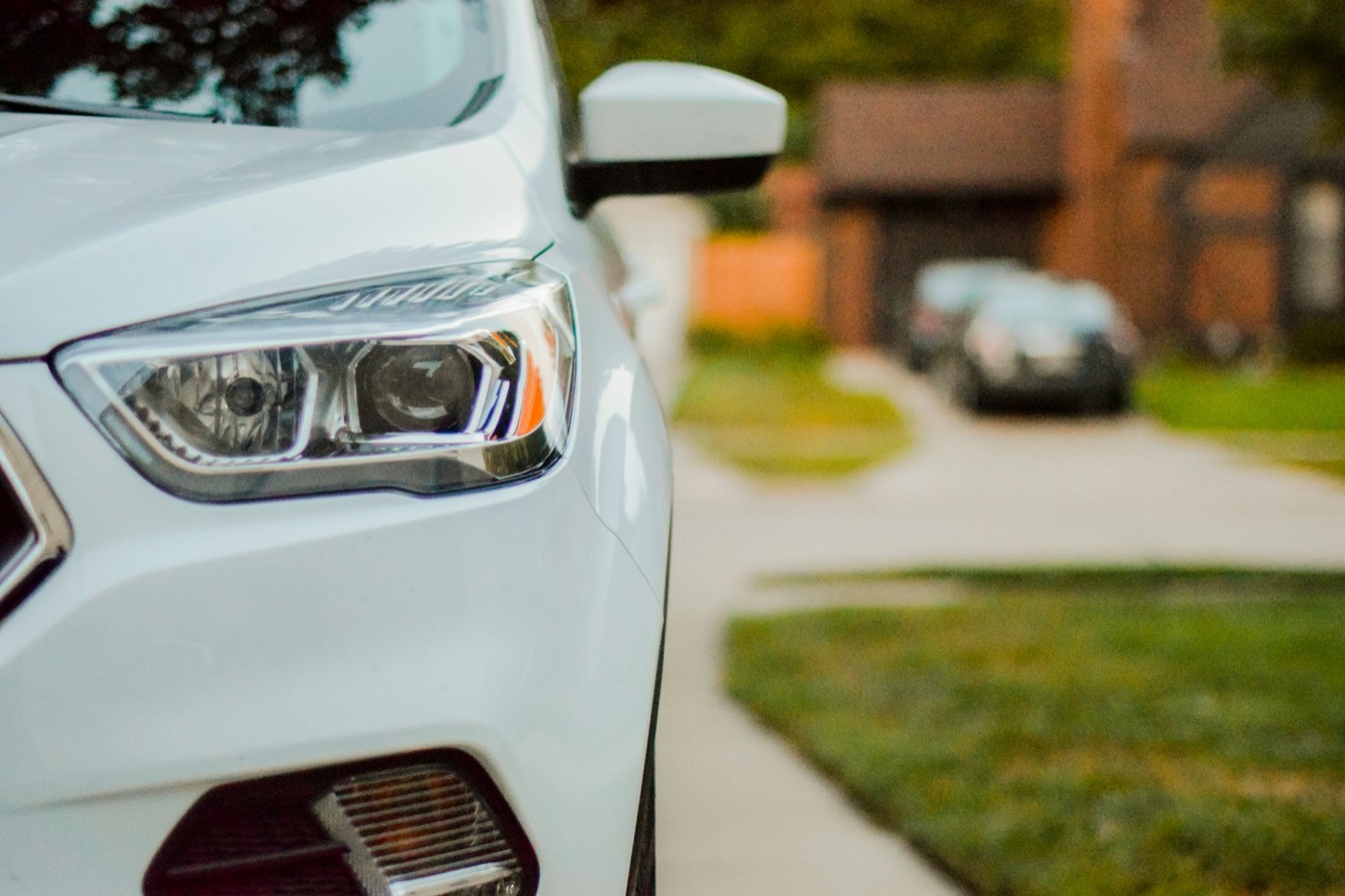 The front of a white car parked in a residential street