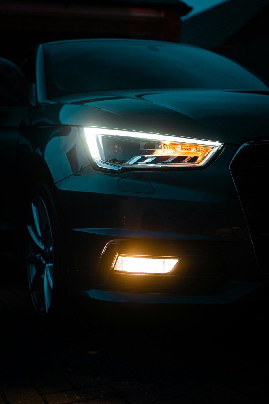 A car headlight lit against a dark background